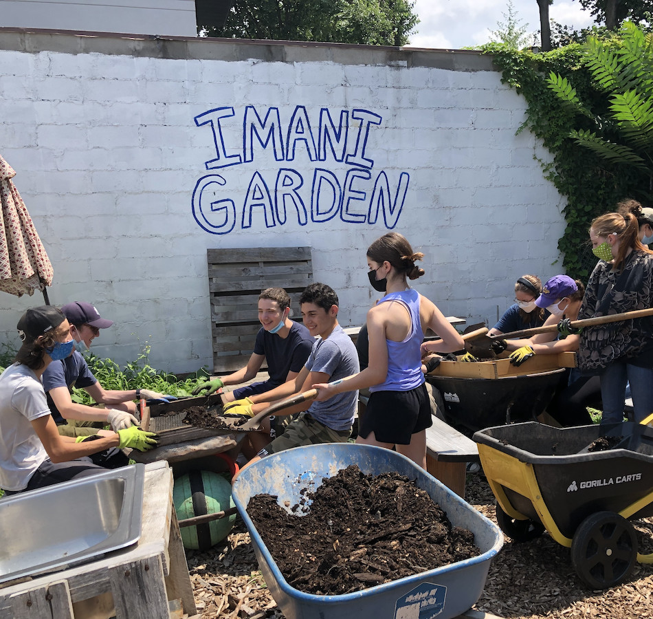 Teen volunteers shovel dirt at Imani Gardens in Crown Heights.